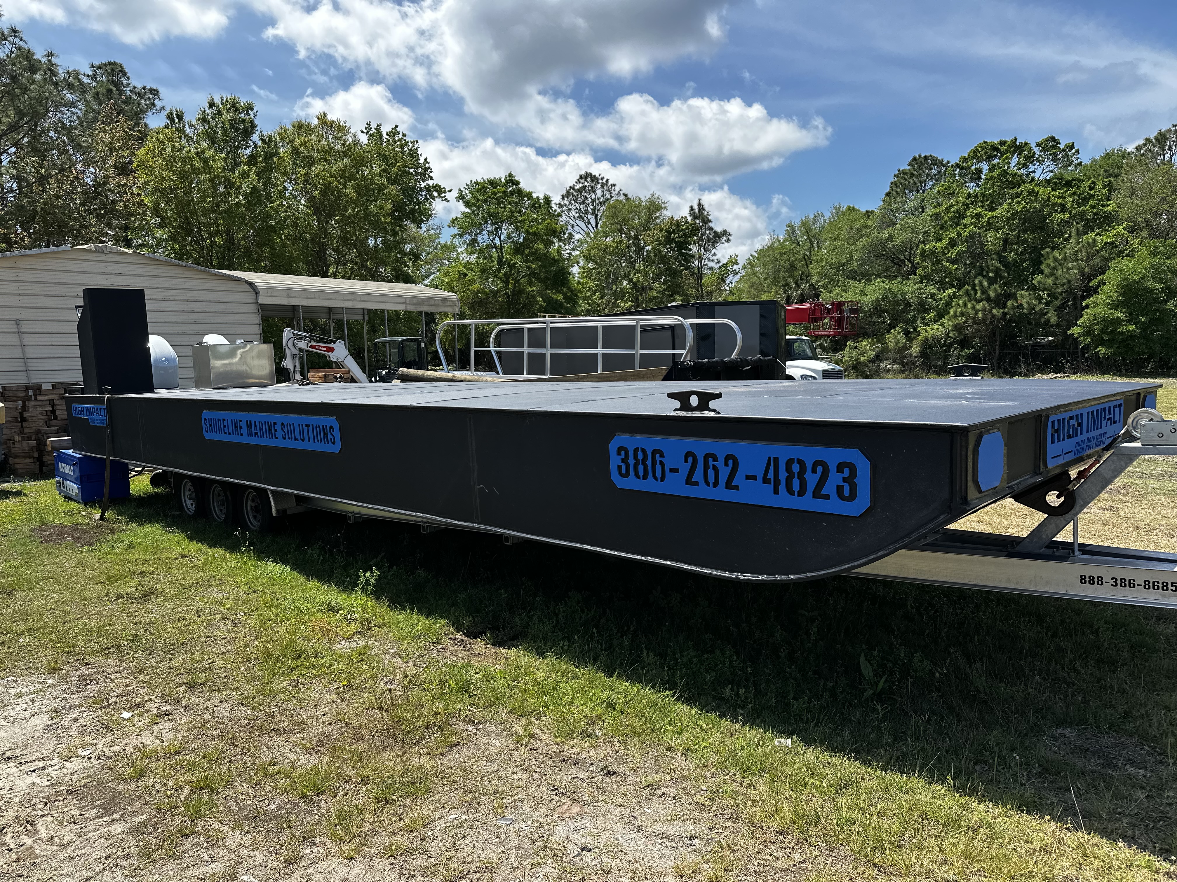 Ready to deliver Shoreline Marine Solutions barge with blue highlights on a trailer.